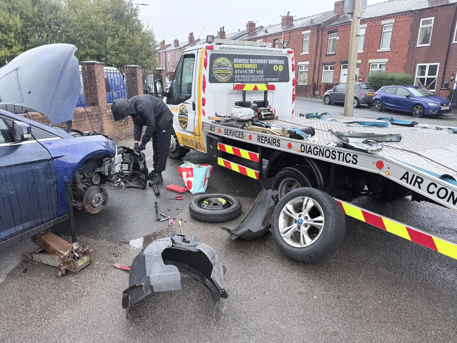 Recovery operator attending to a vehicle beside the recovery truck